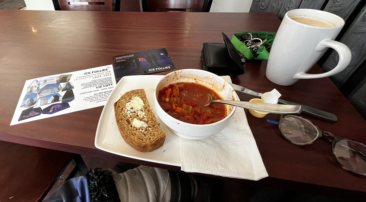 Un bol de soupe aux tomates, avec une généreuse tranche de pain, sur la table d'un café.