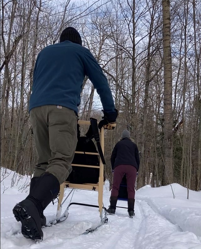 Deux personnes font de la trottinette des neiges dans un sentier enneigé.