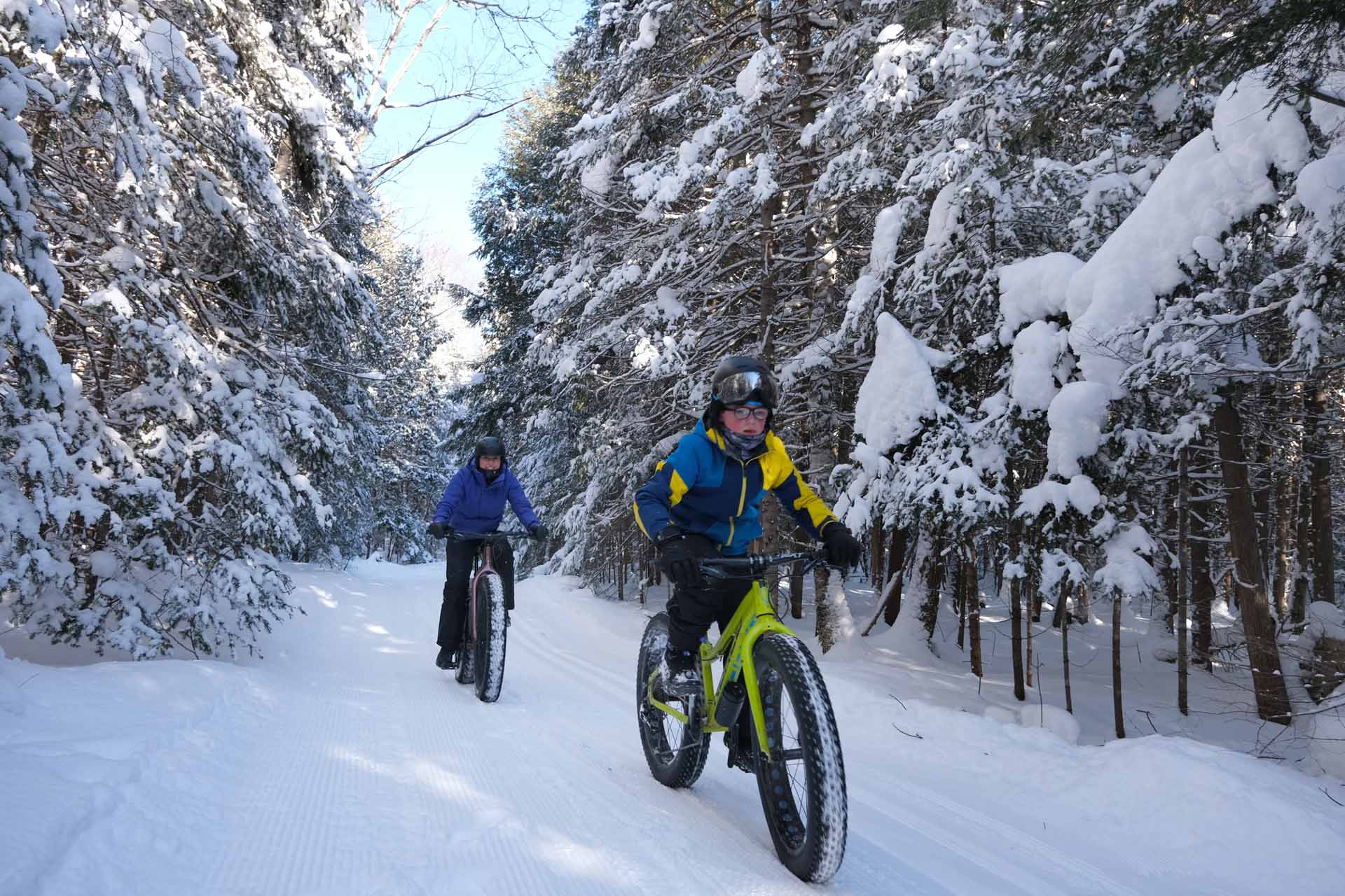 Deux cyclistes roulent dans des sentiers enneigés.