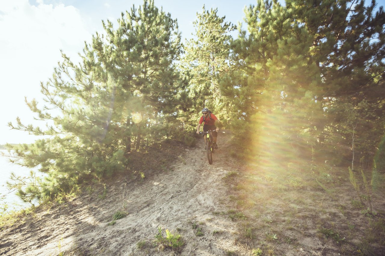 Un vélo de montagne s'avance dans des dunes, entre des arbres, à Kenora. 