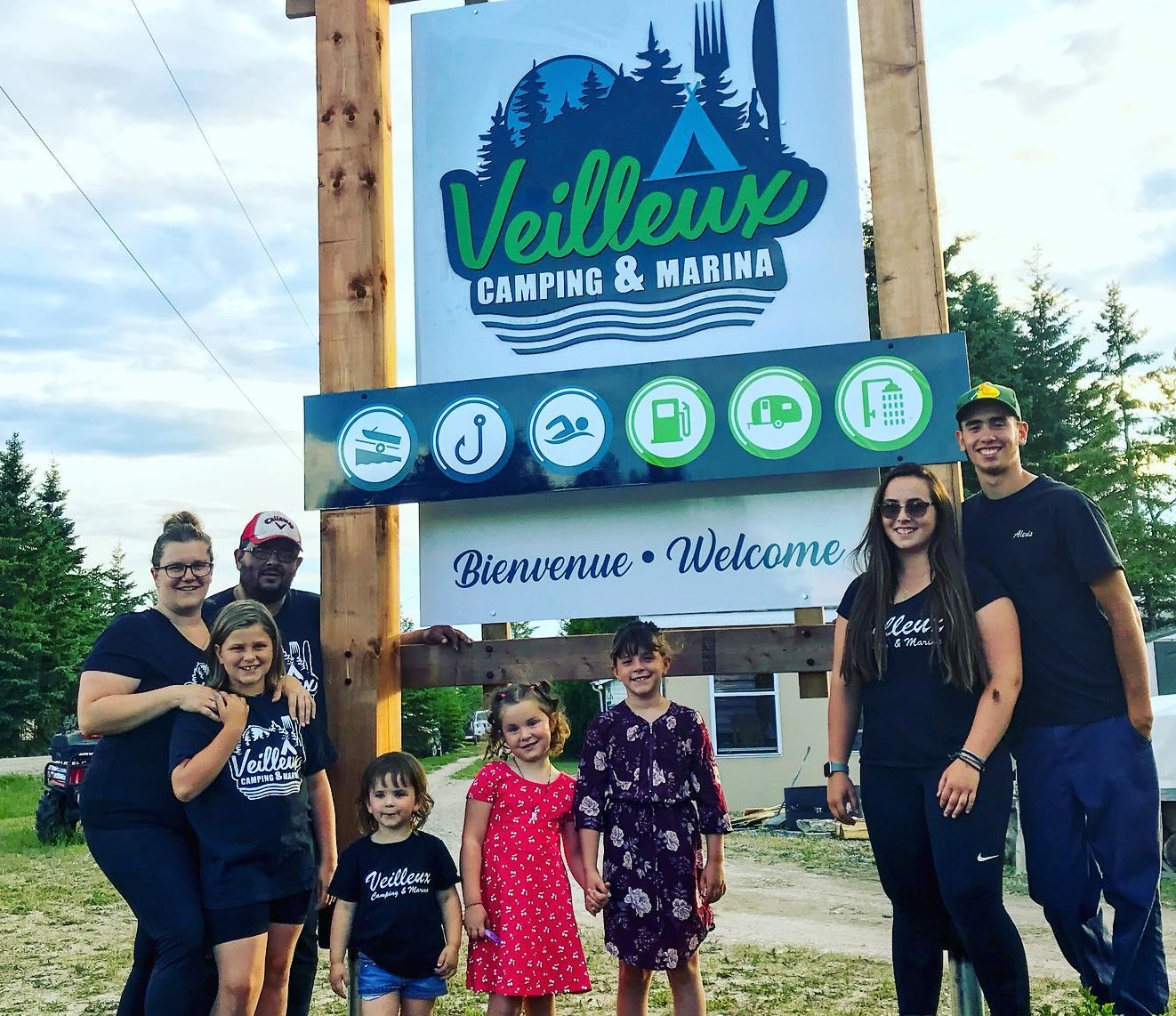 La famille Roy - deux parents et six enfants - est attroupée autour du panneau à l'entrée du camping