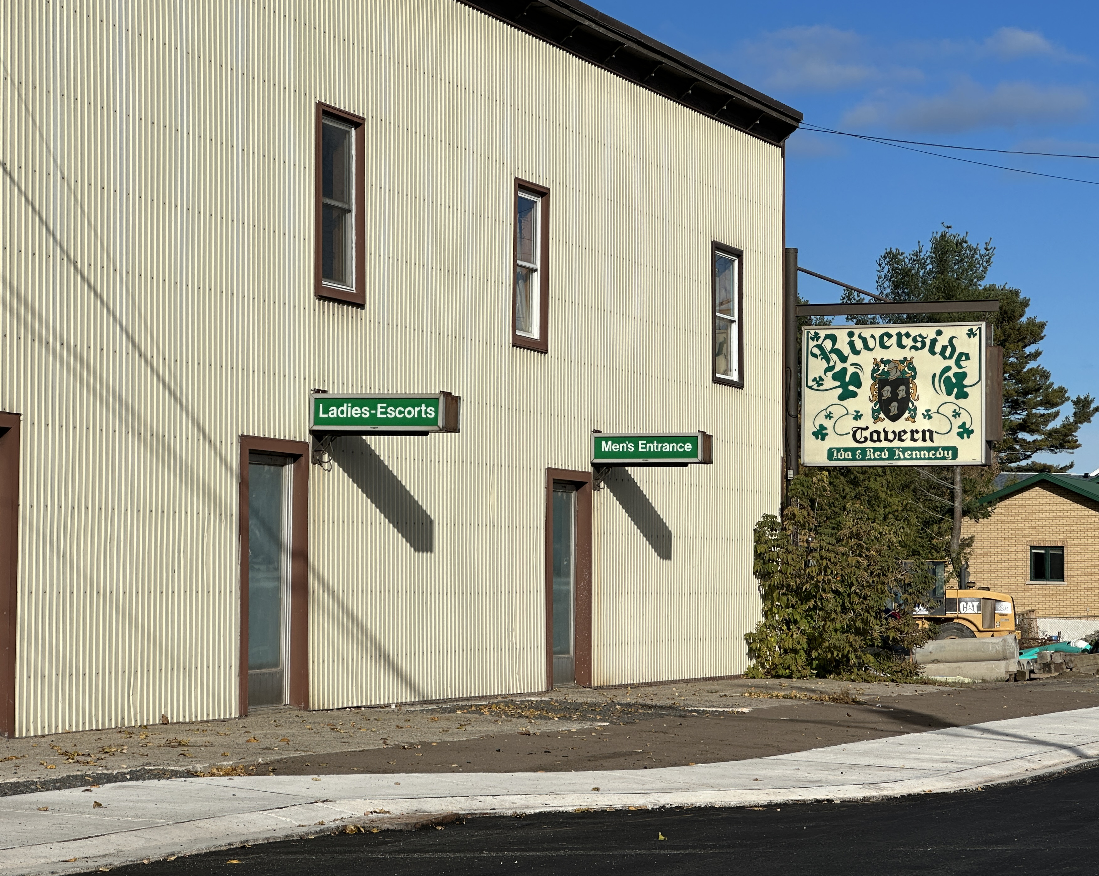 Deux portes sur le côté de la taverne Riverside à Blind River, l'une avec un panneau indiquant « Escortes pour dames » et l'autre « Entrée des hommes ».