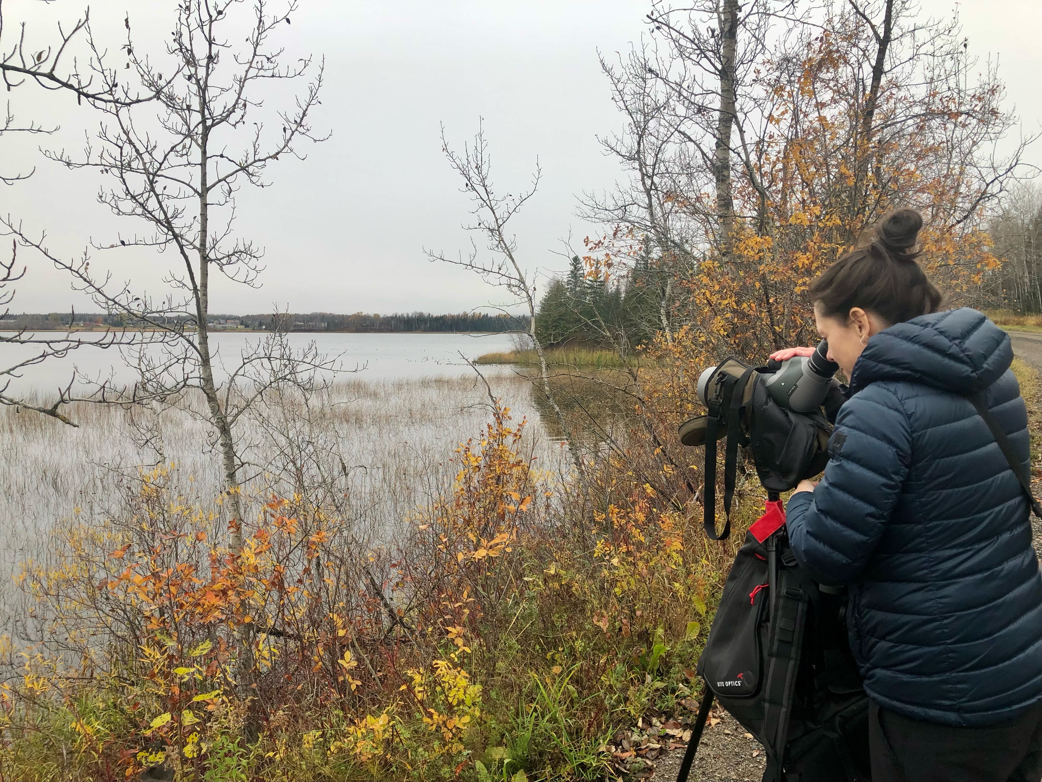 Roxane Filion est installée avec son téléscope surr un sentier près d'un lac, l'automne.