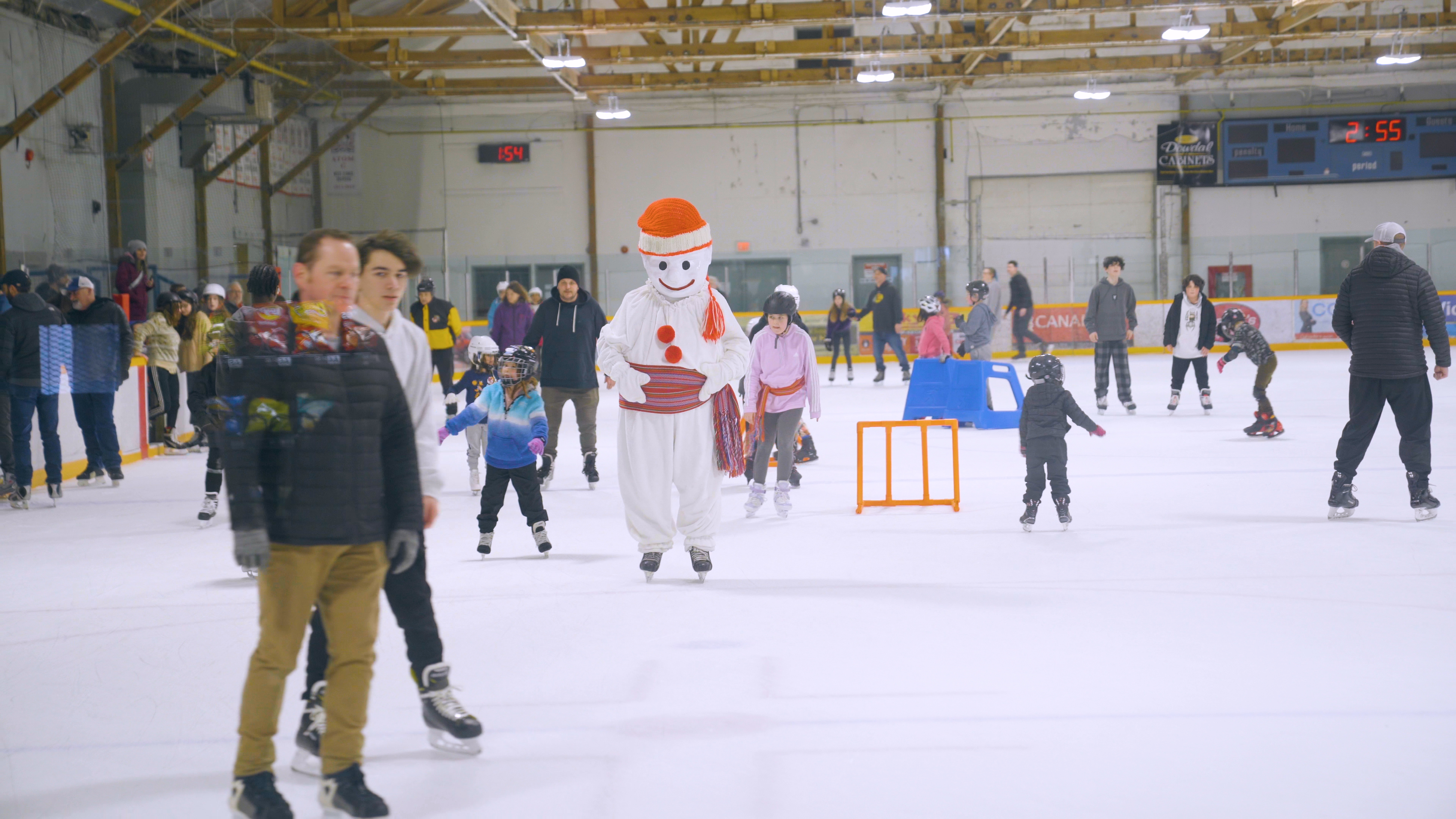 Bonhomme patine au milieu de la foule, dans une aréna intérieure.