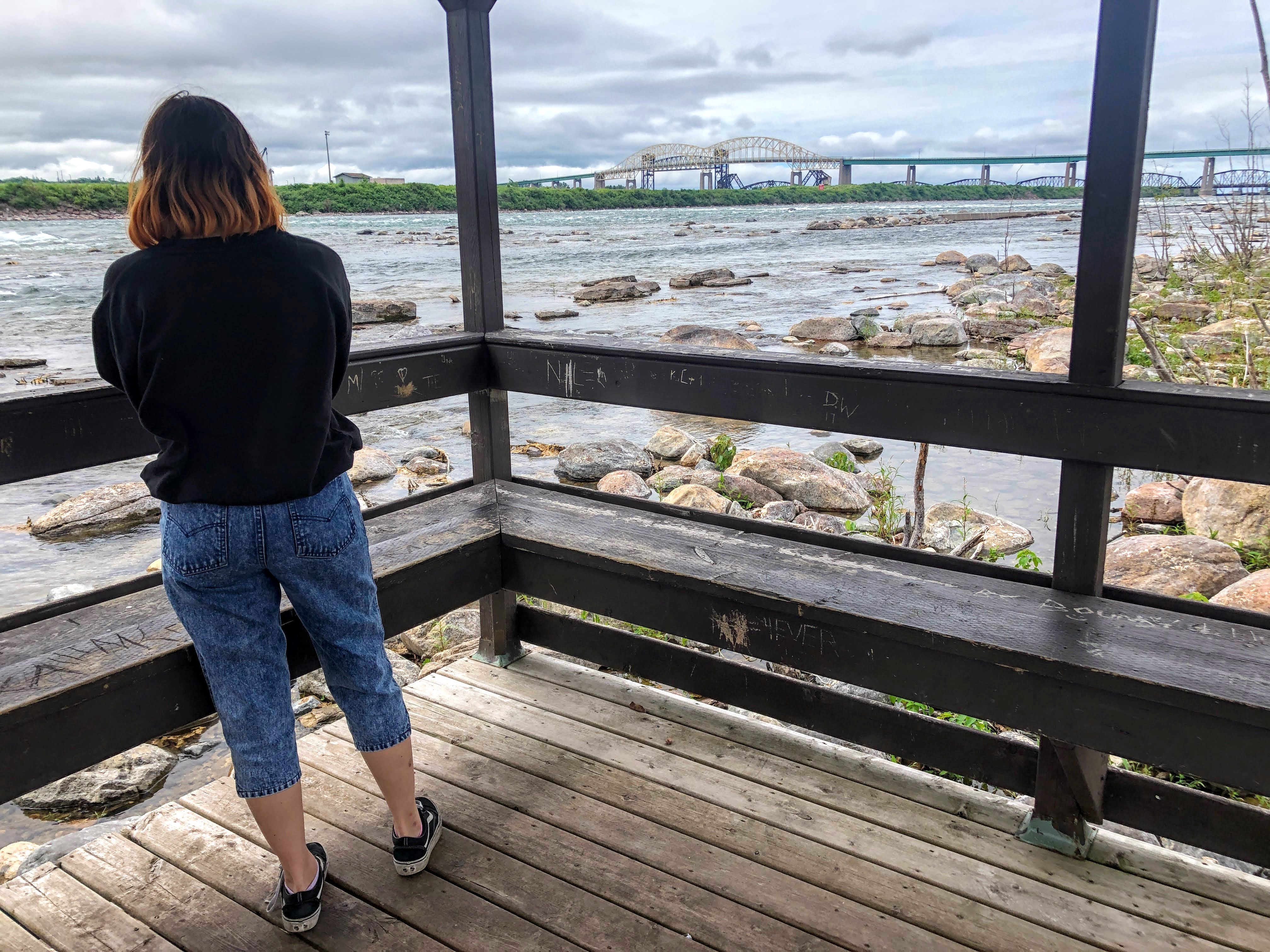 Une jeune femme observe les rapides et l'île Whitefish, à Sault-Sainte-Marie
