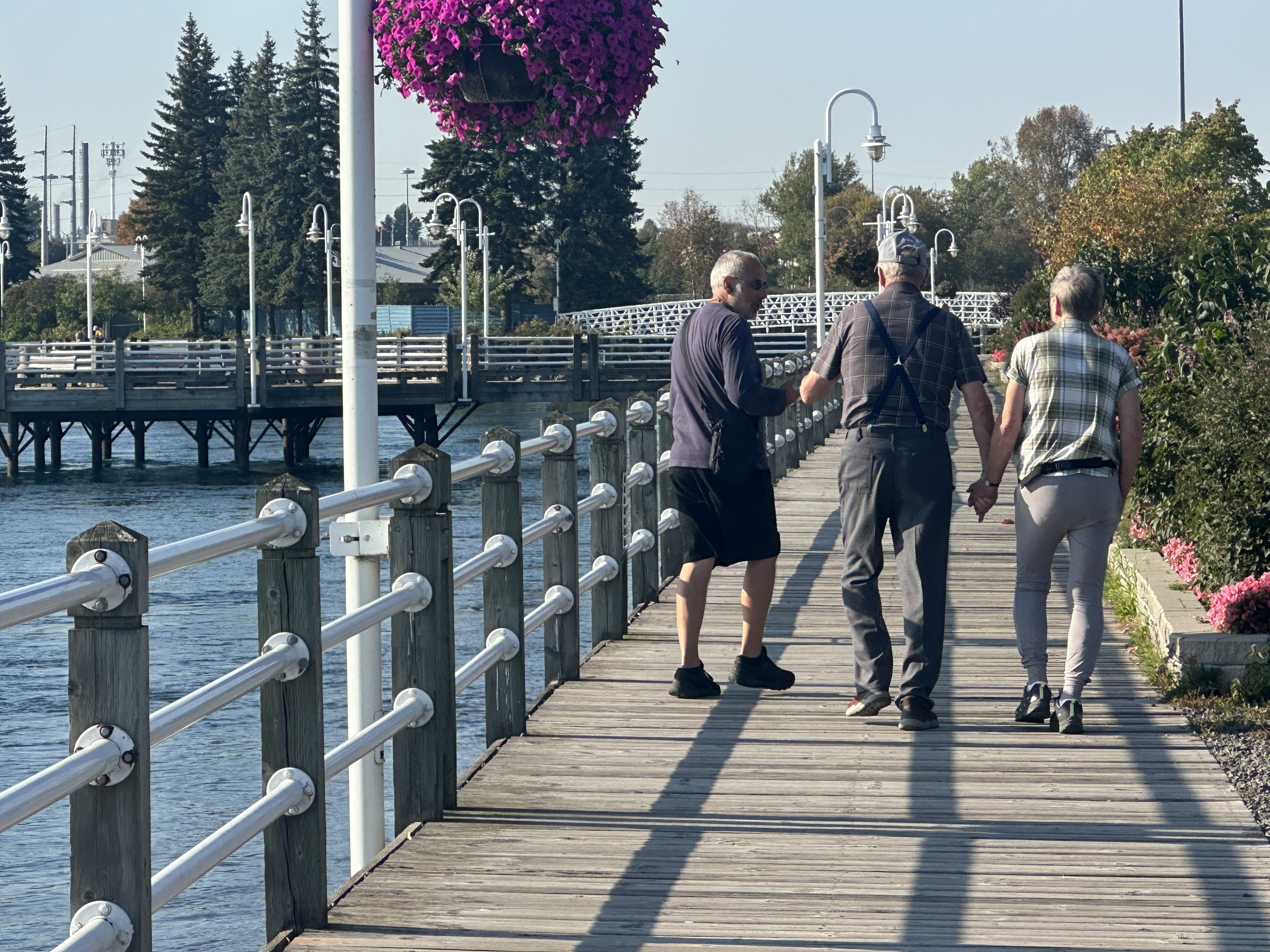 TRois hommes marchent sur le trottoir du Hub Trail, près de la rivière Sainte-Marie