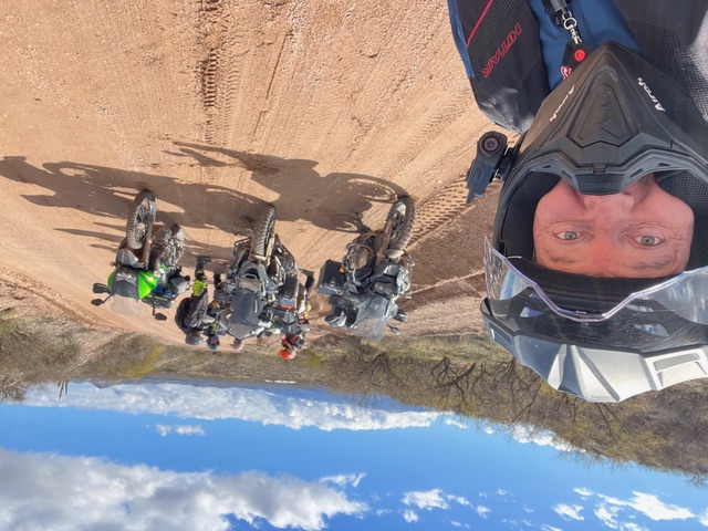 L'Auteur prend un selfie sur une route de terre battue. Un groupe est derrière lui.