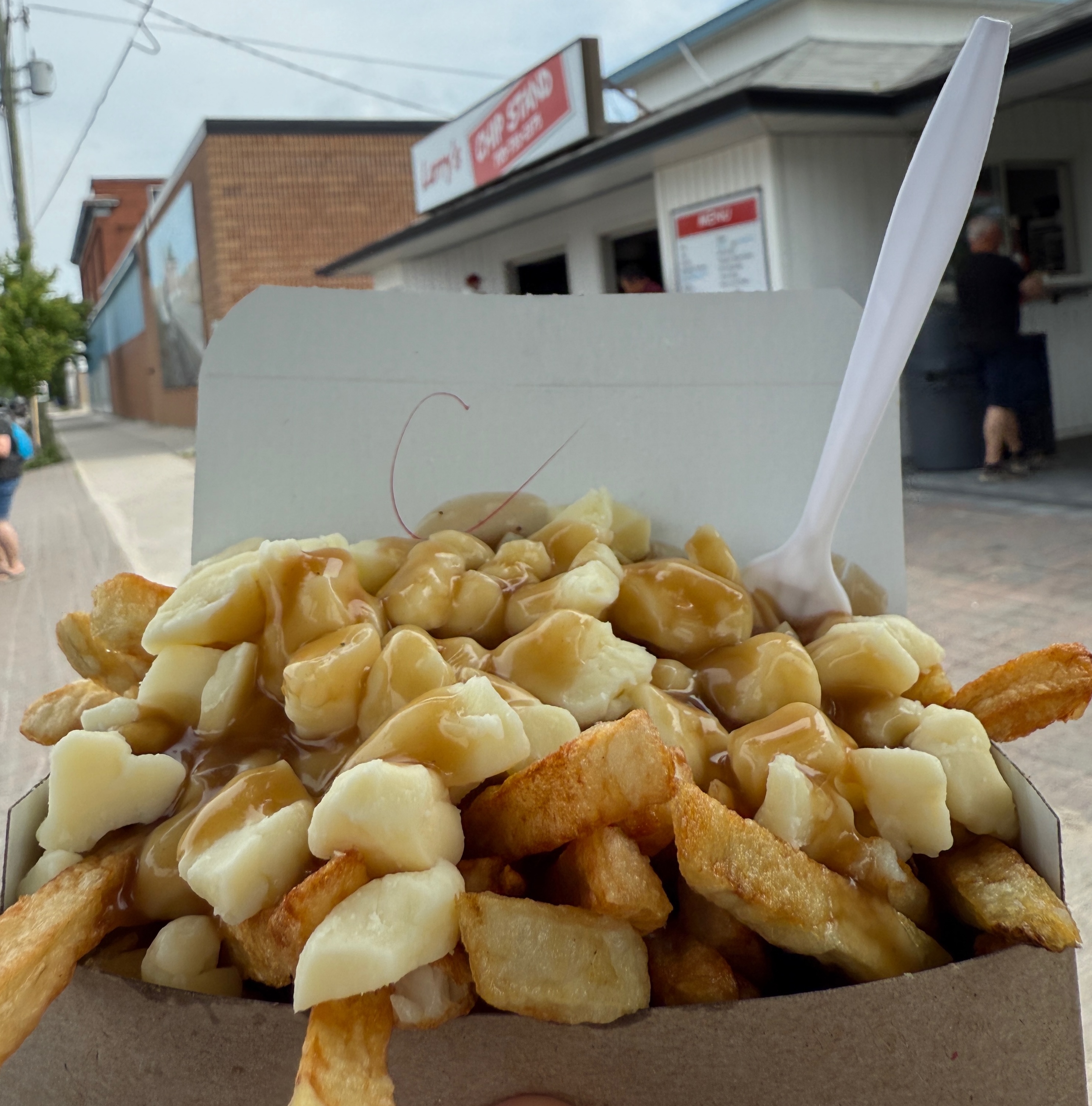 En avant-plan, une poutine. On devine en arrière-plan la pataterie Larry's, sur la rue Main, à Sturgeon Falls. 