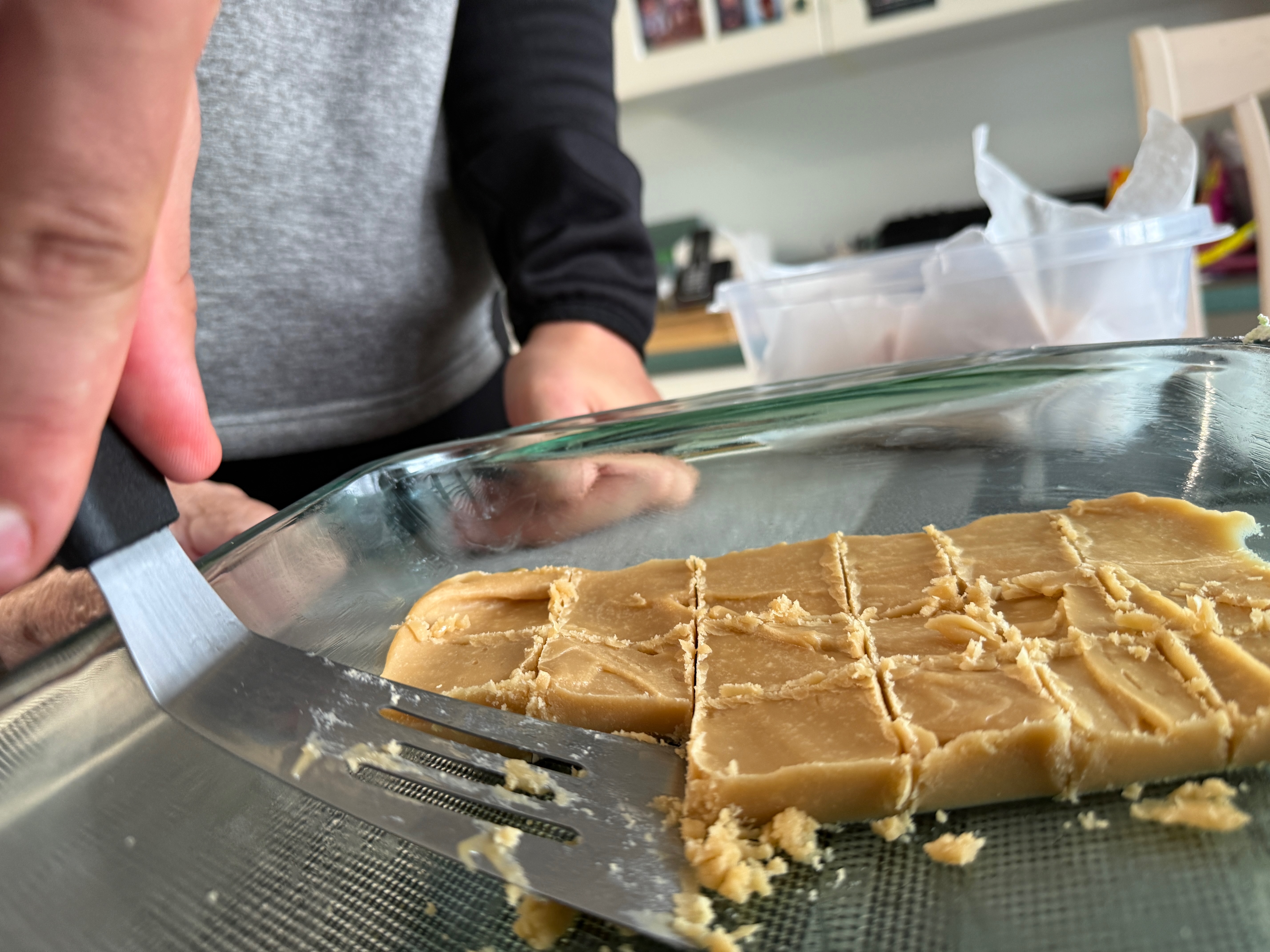 Une personne coupe des morceaux de sucre à la crème.