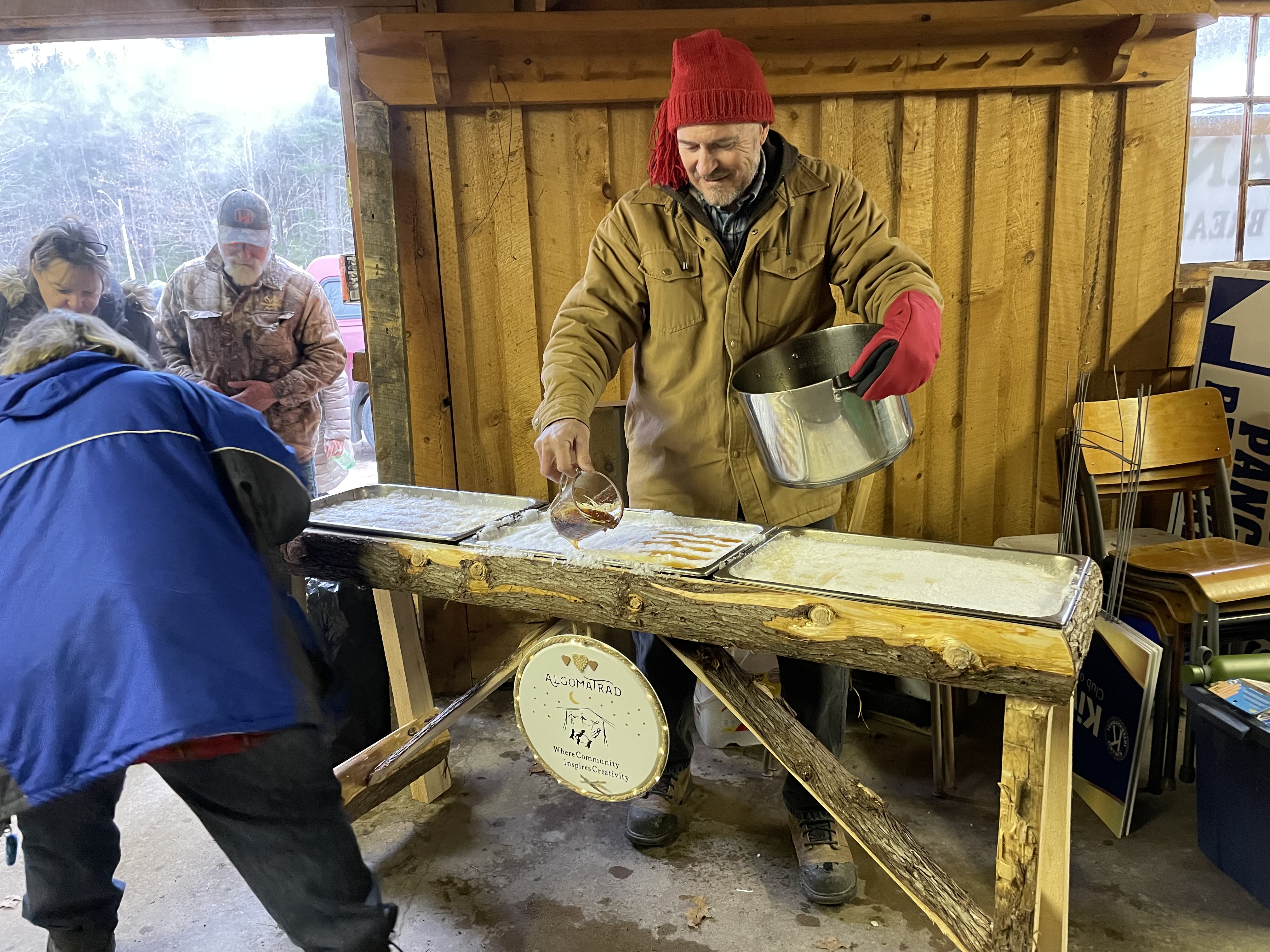 Un homme verse de la tire d'érable sur la neige.