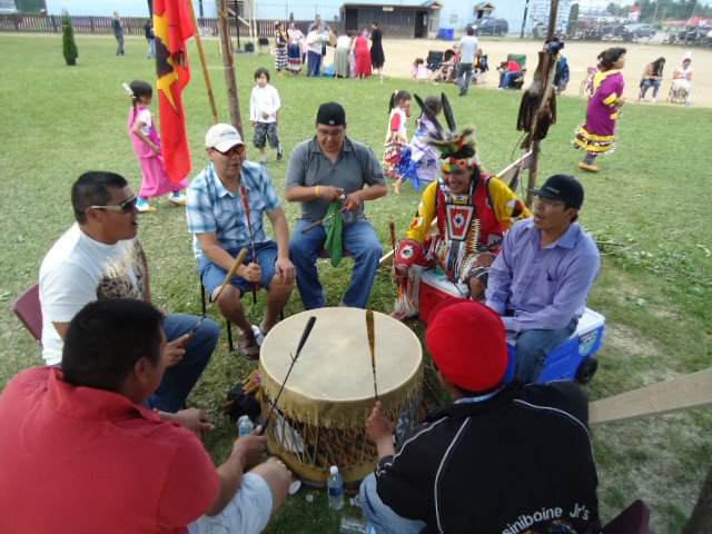 Des batteurs chantent en cercle lors du pow-wow communautaire de Red Lake, sous le regard des participants.