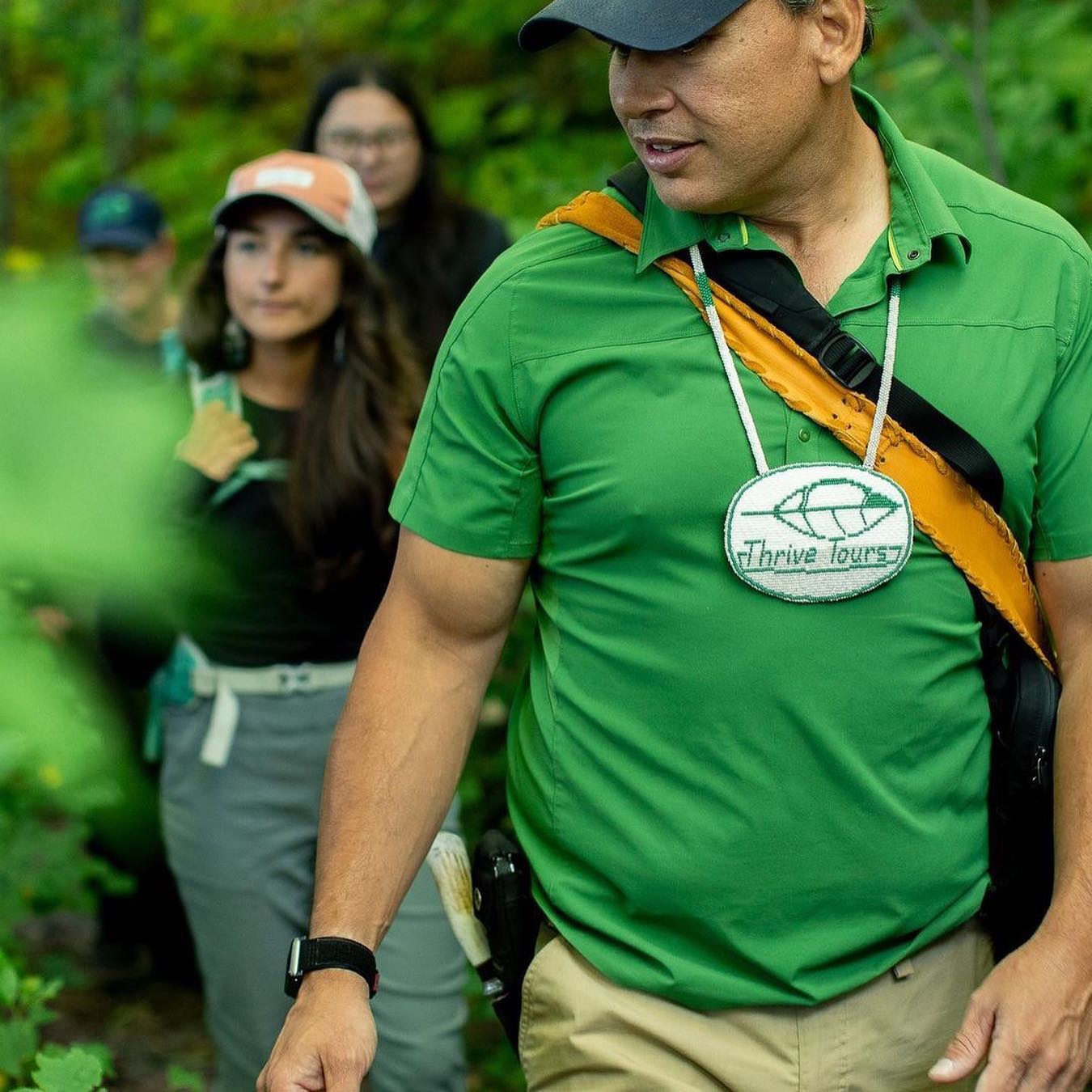 Un guide de Thrive Tours accompagne un groupe à travers une forêt dense, leur décrivant les plantes au fur et à mesure qu'ils les croisent.