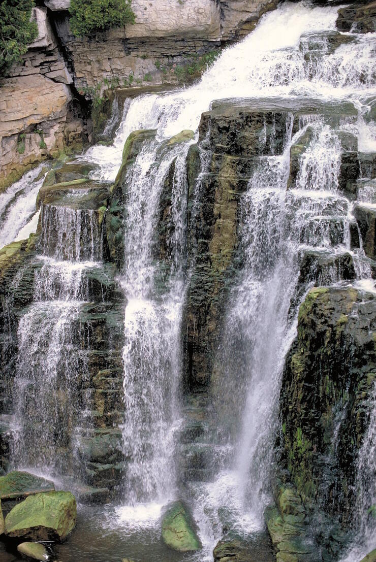 water cascades over a tall waterfall with rocky pillars