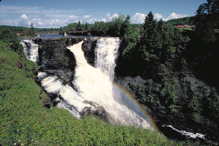 Large waterfalls with a bridge over it. 