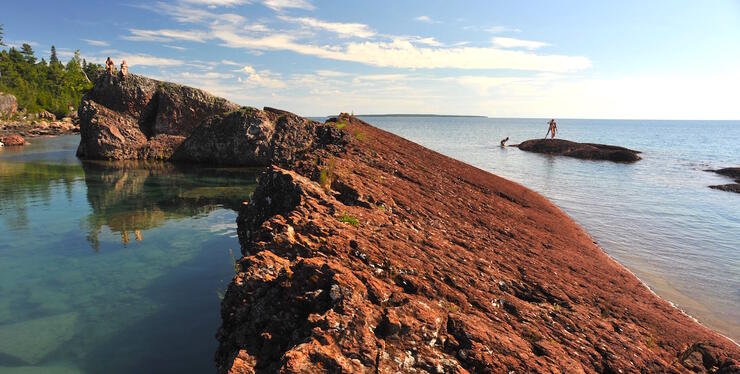 People on rocks and people swimming in beautiful clear water.