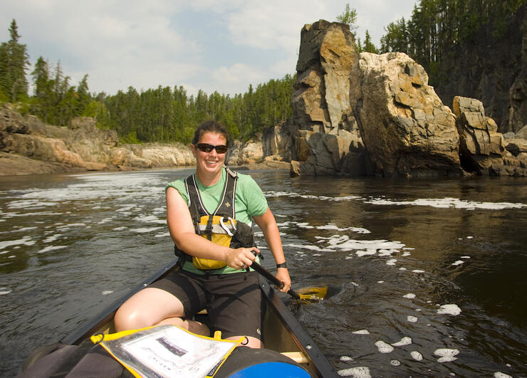 Woman paddling a canoe on a river with a map in front of her