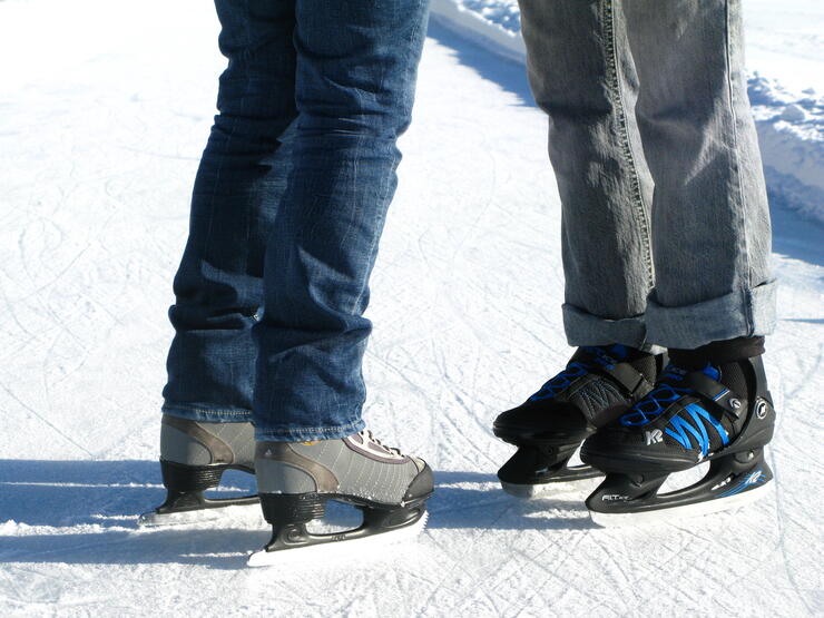 Close-up shot from knees down of a woman in skates facing a man in skates