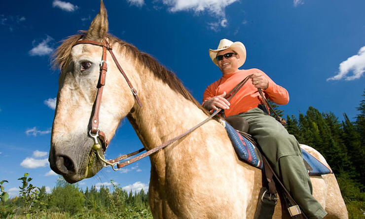 Man in a cowboy hat riding a horse. 