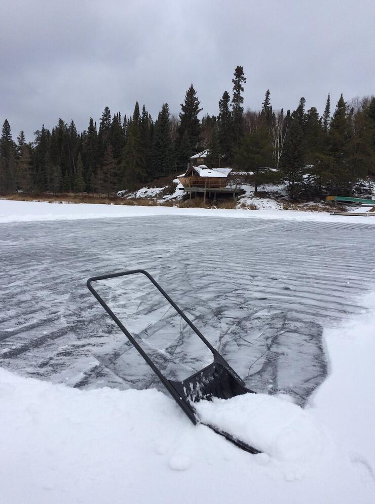 Shovel finishing clearing the ice with yurt in background.