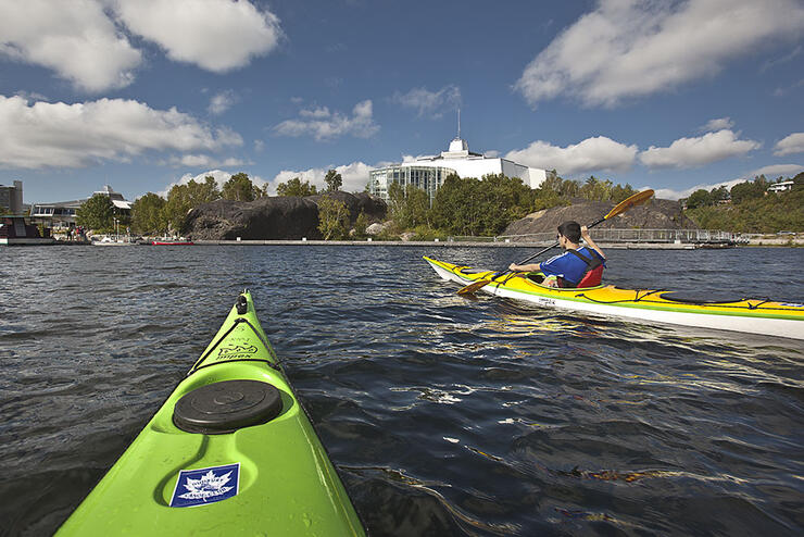 Man is a yellow kayak and green kayak on left