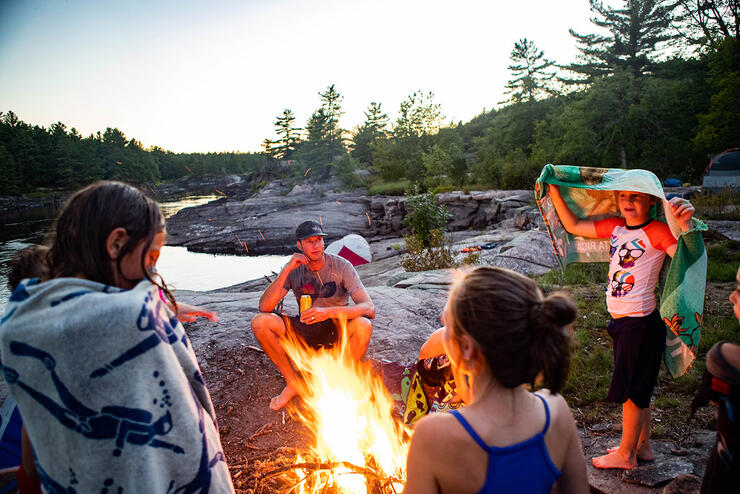 People gathered around a campfire at dusk.