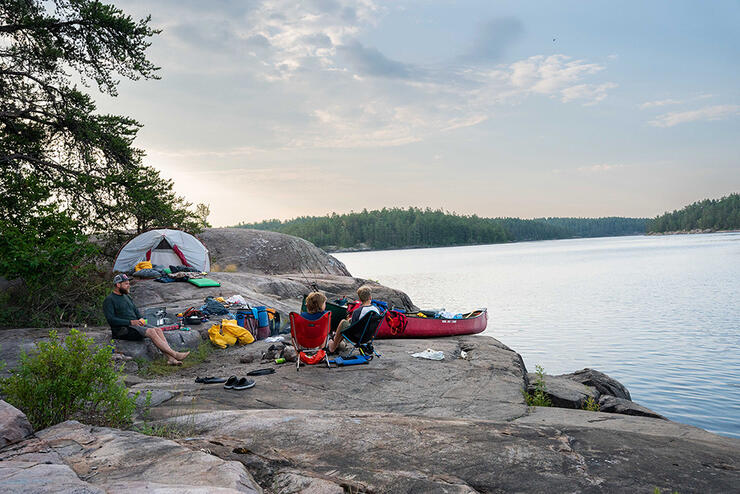 Campsite set up on rocky shore next to river.