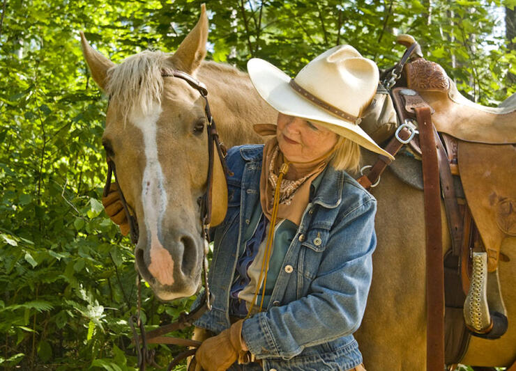 Woman standing beside a harnessed horse. 