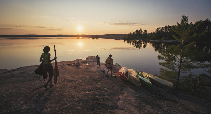 People on a flat rock point with canoes