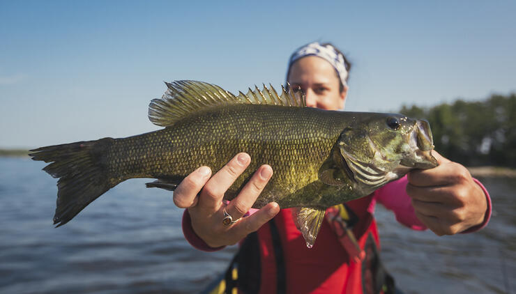 Woman holding a fish while sitting in a canoe